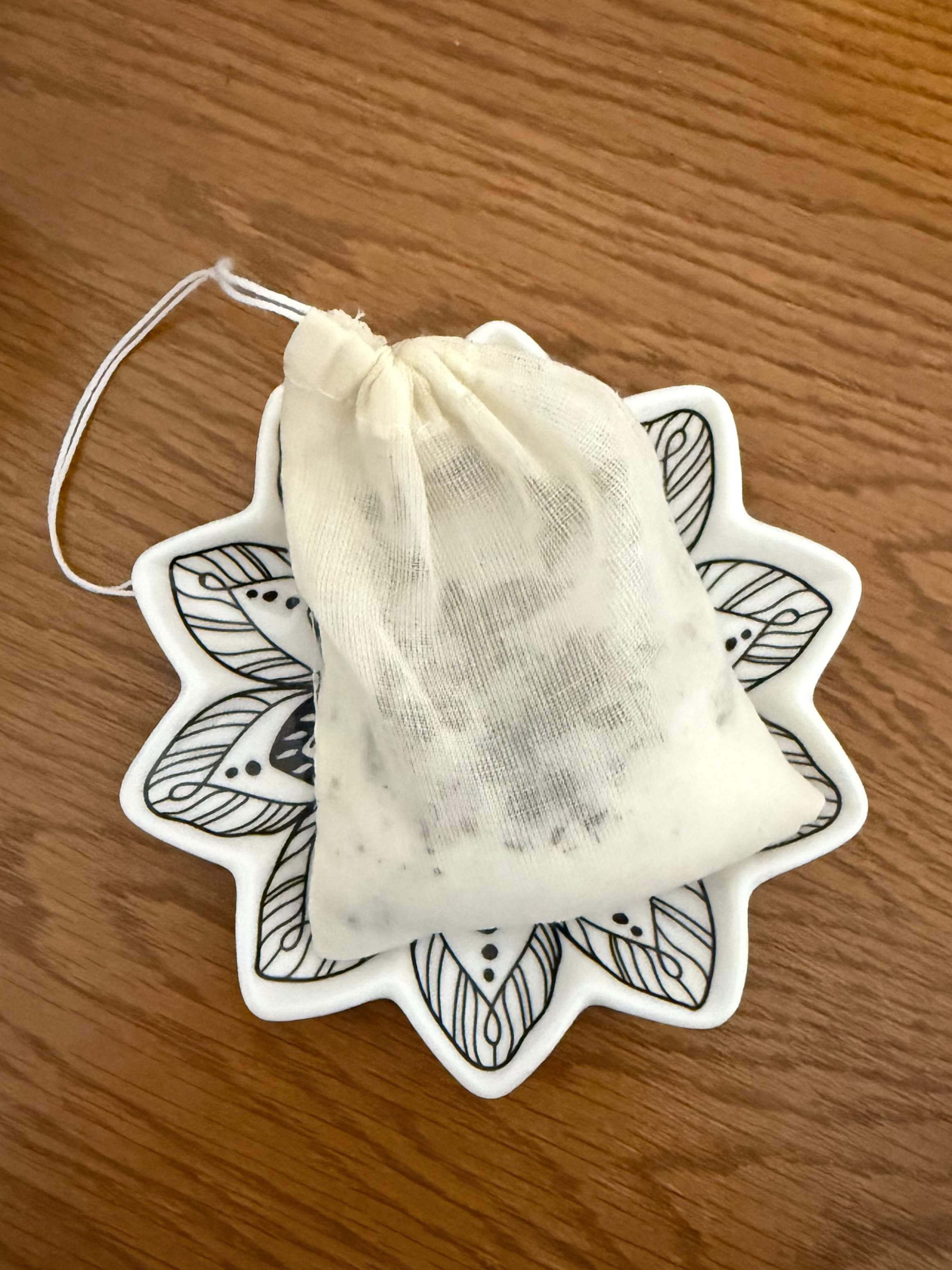 Decorative tea bag with mandala design on a wooden surface